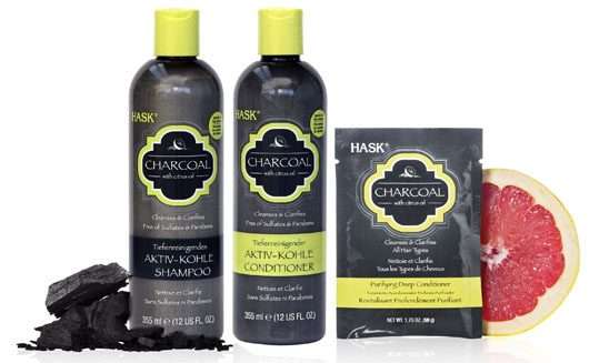 HASK Charcoal Shampoo, Conditioner und Kur neben Grapefruit und Kohlestückchen
